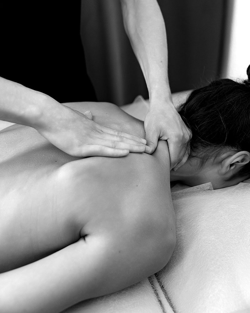 A client at a Medical Spa Nassau County gets a relaxing back massage on a plush white massage table.