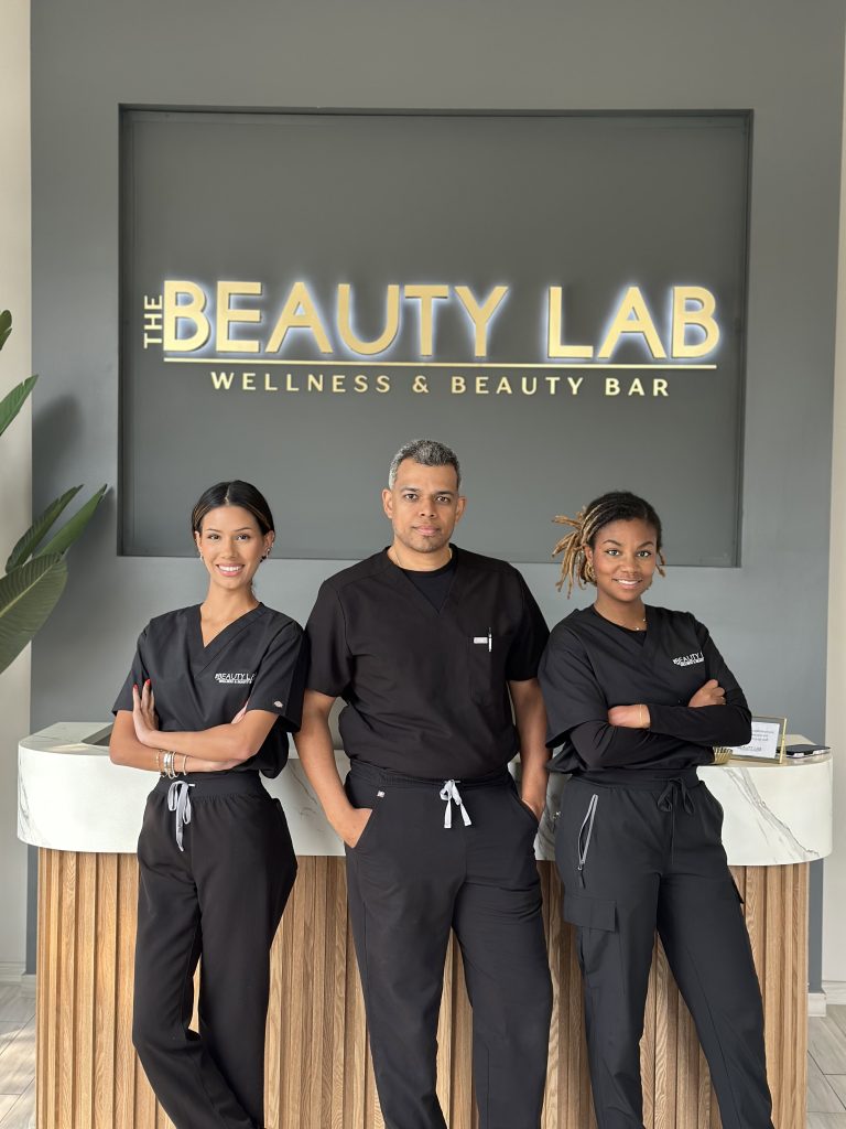 Three people in black scrubs smile together outside The Beauty Lab, a leading medical spa in Nassau County.