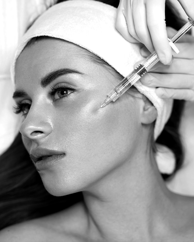 At a Medical Spa Nassau County, a woman with a headband receives a cosmetic injection in her face.