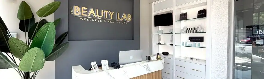 Reception area of The Beauty Lab features a marble desk, green plant, and product display shelves.
